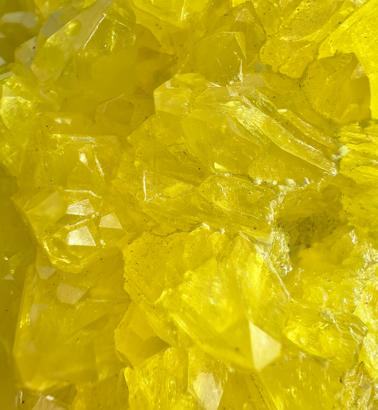 Bright yellow sulfur crystals up close, showing sharp natural crystal faces