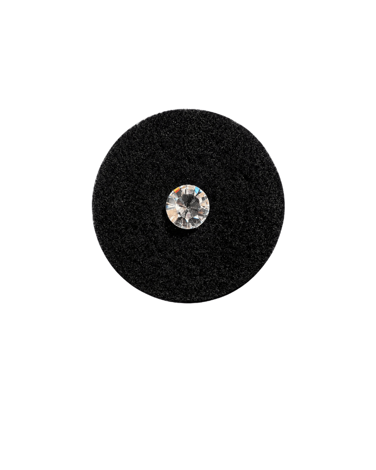 A faceted clear quartz gem resting on a disc of black velvet
