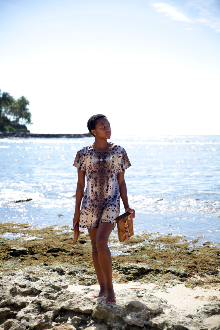 Woman walking along a rocky shoreline in a patterned print dress