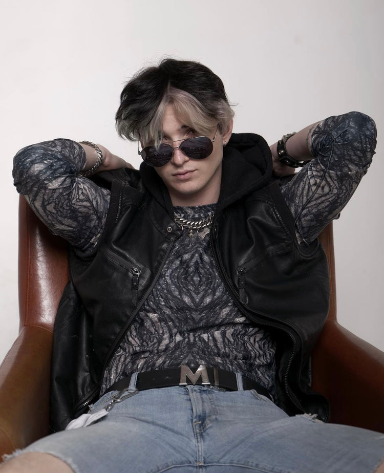 Young man in sunglasses wearing a dark crystal-print long-sleeve top under a leather jacket